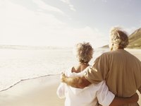 A retired couple walking along the beach.