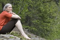 A woman sitting on a rock in the forest.