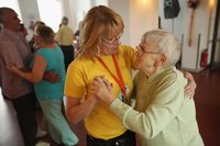 An adult daycare worker dancing with a client.