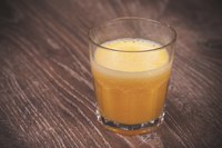 A glass of orange juice on a wooden table.