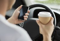 A businessman is holding a coffee driving for work.