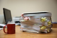 A large stack of paperwork sitting on an office desk.