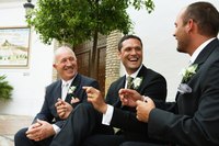 The father of the groom laughing with his son and the best man after the wedding.