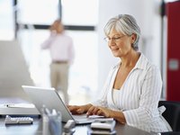 Woman working on budget in office with laptop and calculator on desk.