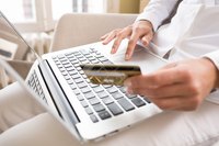 Woman holding credit and laptop while shopping online.