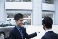 Salesman giving keys of new car to buyer