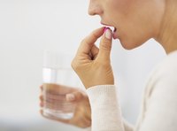 Woman taking a vitamin supplement with a glass of water.