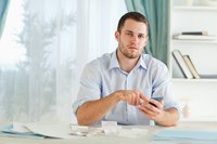 Businessman filling out tax papers and holding calculator