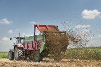Manure being spread on field by large farming machine