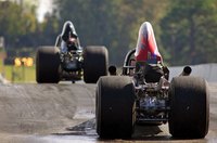 The back of two dragster-style cars lining up on a race track.