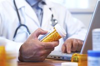 Doctor with prescription medicine, laptop and stethoscope.