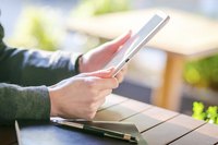 A woman is holding a tablet in her hands.