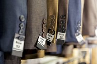 Close-up of suits' sleeves on rack in store.