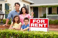 Family holding a key next to a "For Rent" sign.