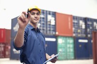 A dock worker is standing by containers.