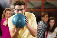 Young man with friends gets ready to roll a bowling ball.