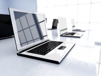 Several laptops in a row, sitting on a desk in a modern office