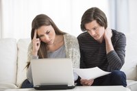 A young couple studies their debt in order to try and figure out the best way to get out of their financial mess