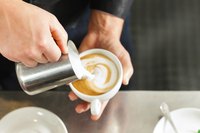A barista makes a cappucino in a cafe.