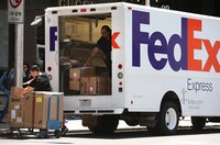 Two Fed Ex employees unloading a truck delivery.