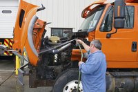 Man washing the inside of a truck's hood.
