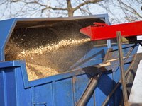 A wood chipper fills tha back of a loader.