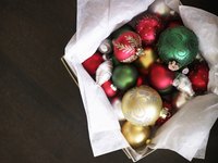 An overhead view of a basket of red, green, white and gold Christmas ornaments.