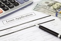 Calculator, pen, money on a loan application.