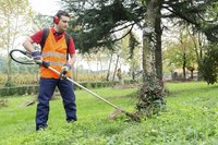 Landscaper trimming the grass with a weed wacker.