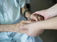 A close up of a woman holding an elderly woman's hands.