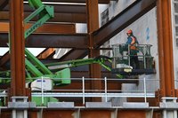 A construction worker in a mechanical lift on a work site.