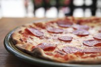 A pepperoni pie sits on the counter of a pizzeria.