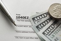 An overhead view of money and a pen on an income tax form.