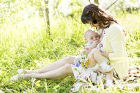 A woman nurses her baby outside.