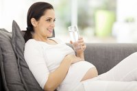 A pregnant woman holding a glass of water.