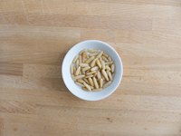 Bowl of pine nuts on a wooden table.