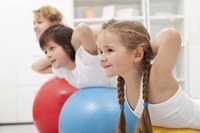 Kids using a large ball to do exercises.