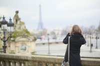 A young woman taking a photograph in Paris.