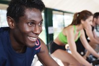 Thre gym members cycling at the gym.