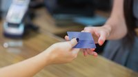 A customer hands a credit card to a cashier