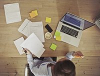 An overhead view of a woman doing accounting at home at the table.