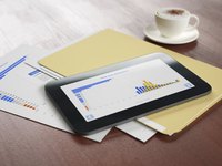 A financial portfolio and smart tablet on a table next to a cappuccino.
