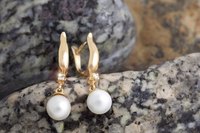 Pearl earrings displayed on stone.