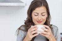 Woman smelling cup of coffee