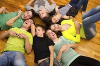 A group of teenagers lying on the floor in a circle together