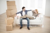 A couple is sitting in their living room by their stuff.