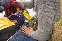A close-up of a woman rummaging through used clothing.