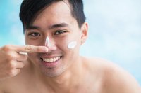 Man applying sunscreen on his face in pool.