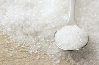 A spoon filled with white sugar.