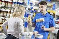 A hardware store employee compares products for a customer